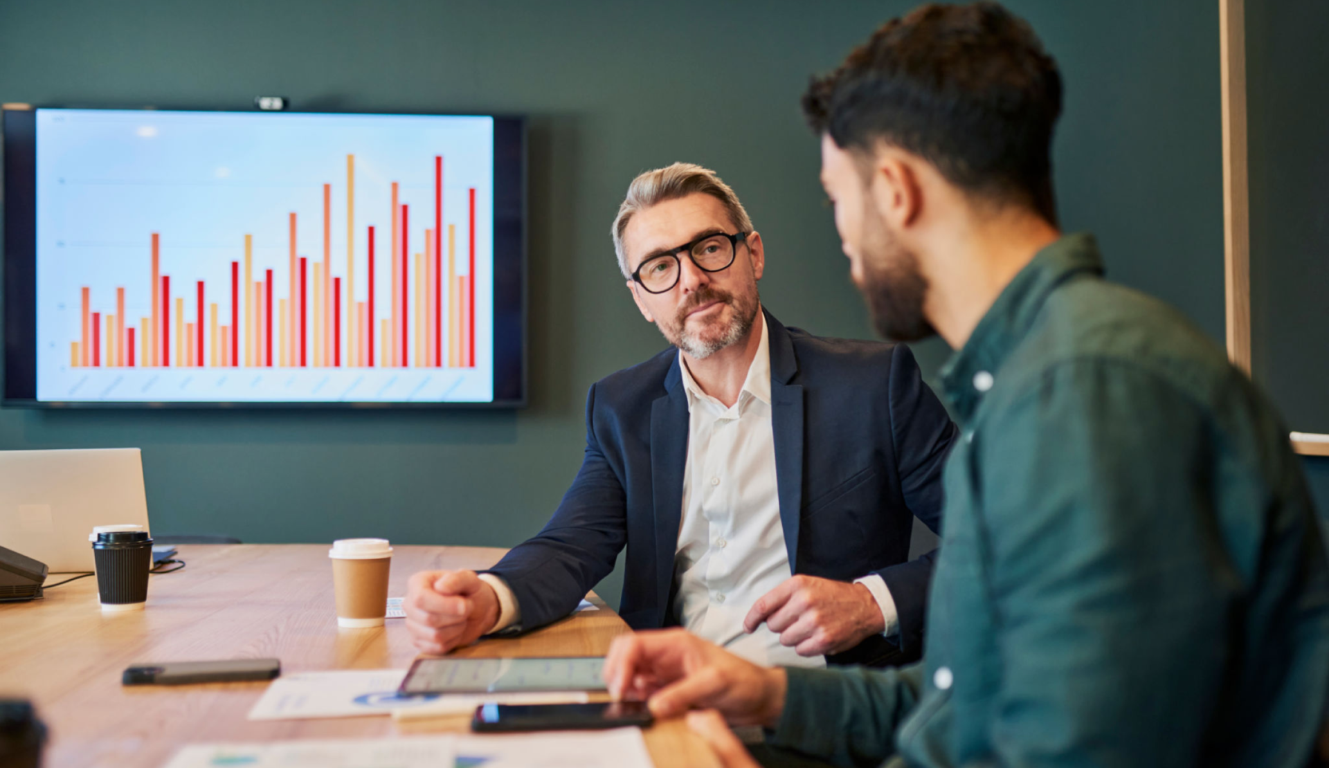 Professionals analyzing bar chart on screen